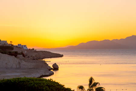 Sunrise over the red sea. Beautiful bright sky with sun rays and morning clouds. Sea and boats. View...