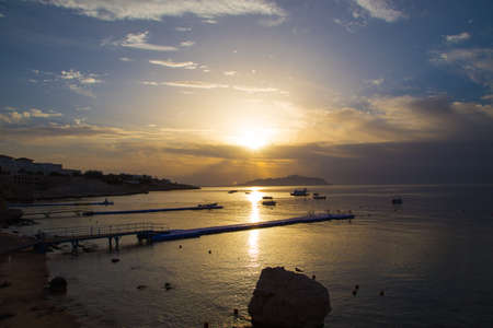 Sunrise over the red sea. Beautiful bright sky with sun rays and morning clouds. Sea and boats. View of Tiran Island. Egypt, Sharm El Sheikh. Tourism and travel. Rest and vacation.の写真素材