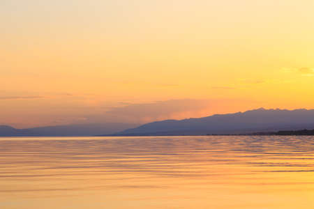 Beautiful sunset on a lake in the mountains. Kyrgyzstan, Issyk-Kul Lake.の写真素材