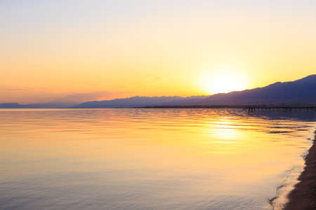 Beautiful sunset on a lake in the mountains. Kyrgyzstan, Issyk-Kul Lake.の写真素材