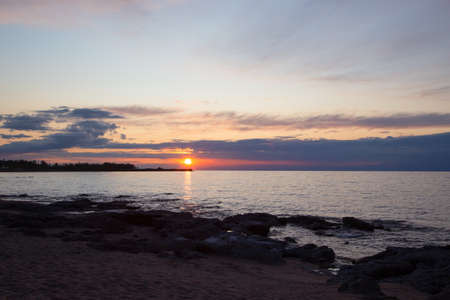 Beautiful sunset on a lake in the mountains. Kyrgyzstan, Issyk-Kul Lake. Bright sky, background in warm colors.の写真素材