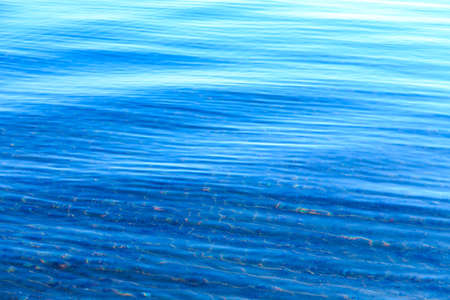 Clear water texture in blue and orange. Background of the ocean and the sea backlit by the sun....