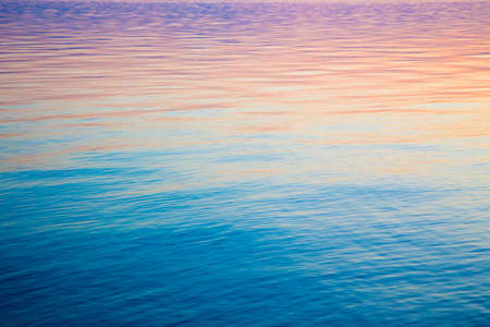 Clear water texture in blue and orange. Background of the ocean and the sea backlit by the sun....