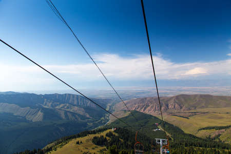 Summer mountain landscape high in the mountains. Tall trees of Christmas trees, ski lift at the ski...