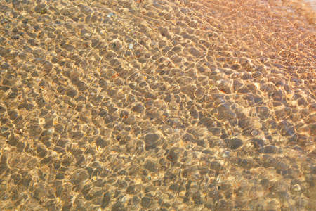 Clear water texture in blue. Background of the ocean and the sea backlit by the sun.