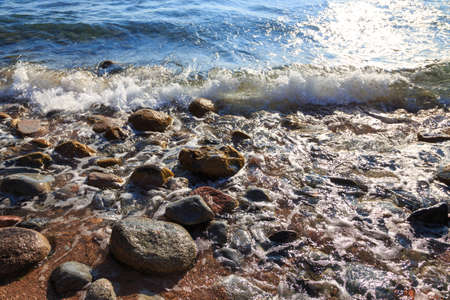 Stones on the sea beach. Pasture winter day. Clear water and sand.の写真素材