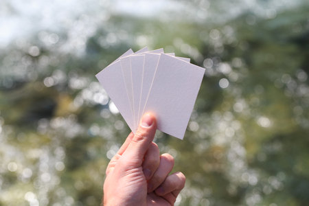 Mockup of a blank white business card in the hand of a muchin against the background of water. For your business card design. Branding Mock up.の写真素材