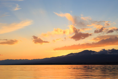 Colorful sunset on the sea. Mountain lake in the rays of the orange sun. Kyrgyzstan, Lake Issyk-Kul. natural backgroundの写真素材