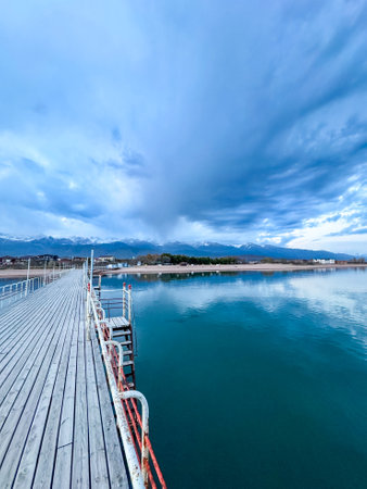 Wooden pier on the seashore. Mountains and clear water. Lake Issyk-Kulの写真素材