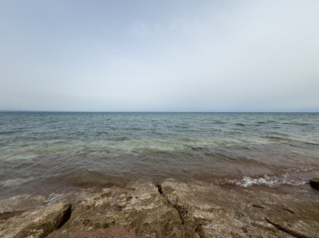 Rocky shore and water of Issyk-Kul under a vast sky.の写真素材