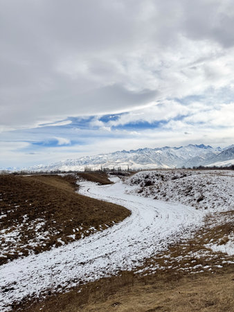 Snow covered mountains in Kyrgyzstan under cloudy winter sky peaceful rural landscape.