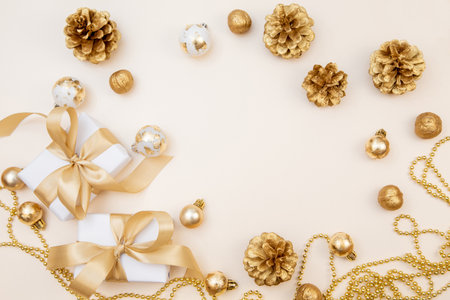Stylish winter layout with white presents, gold bows and sparkling ornaments on beige background. Perfect for greeting cards, web banners or branding.の写真素材