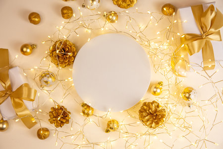 Elegant arrangement with golden gifts, fairy lights and pine cones. Warm Christmas background in soft light for festive designs.の写真素材