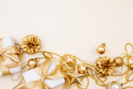 Stylish winter layout with white presents, gold bows and sparkling ornaments on beige background. Perfect for greeting cards, web banners or branding.の写真素材