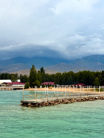 Pier at Issyk Kul Lake in Kyrgyzstan during calm evening. Minimal composition, smooth water surface and pastel sky tones. Concrete pier at Issyk Kul at dusk with soft gradient sky and calm water.の写真素材