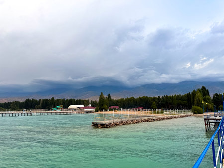 Pier at Issyk Kul Lake in Kyrgyzstan during calm evening. Minimal composition, smooth water surface and pastel sky tones. Concrete pier at Issyk Kul at dusk with soft gradient sky and calm water.の写真素材