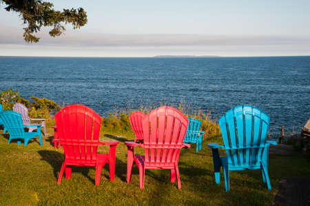 Empty chairs facing the ocean to provide visitors a chance to relax by the Maine seashore in late summer , summer, summertimeafternoon.の写真素材