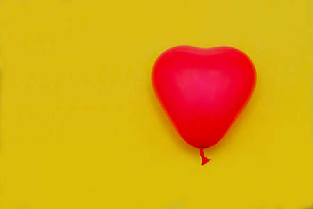 A balloon in the form of a red heart on a yellow background. Valentine's day. love.の写真素材