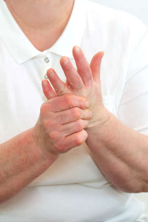 An elderly woman suffering from pain in her fingers close-up. An elderly lady touches her hand, joint pain, joint problems. An elderly woman is holding her sore hand.の写真素材