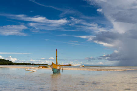 seashore low tide with old boat front view cloudy dayの写真素材