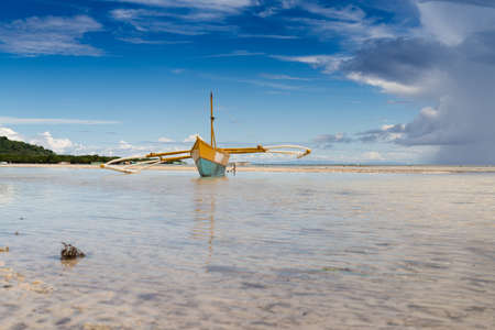 seashore low tide with old boat front view cloudy dayの写真素材