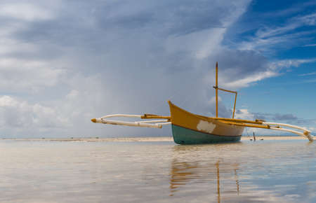 seashore low tide with old boat front view cloudy dayの写真素材