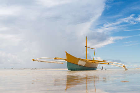 seashore low tide with old boat front view cloudy dayの写真素材