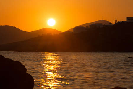 beautiful orange seascape with calm water  sunset above mountains with calm waterの写真素材
