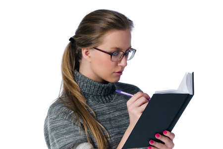 intent looking girl in glasses write in book. white backgroundの写真素材