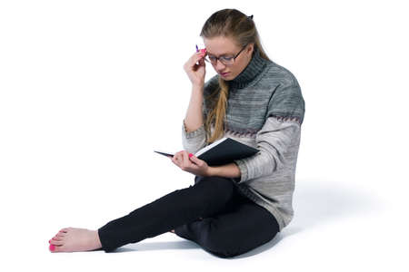 intent looking girl in glasses write in book. white backgroundの写真素材