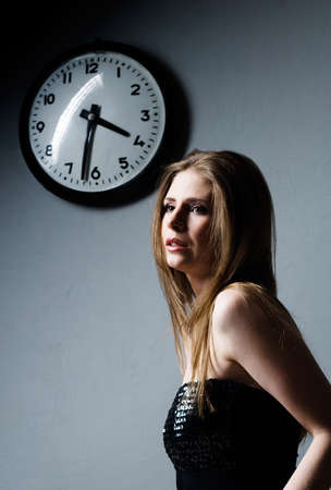 attractive young woman and clock on gray backgroundの写真素材