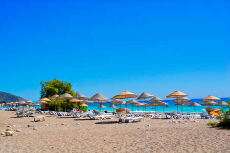 sandy beach with thatched parasols and sun loungersの写真素材