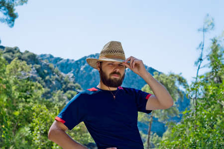 bearded traveler in a hat on a background of mountains