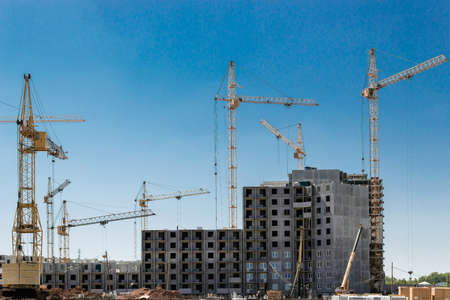 Houses under construction and cranes on the construction site