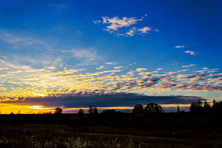 The sun is shining through the clouds at sunset in the evening