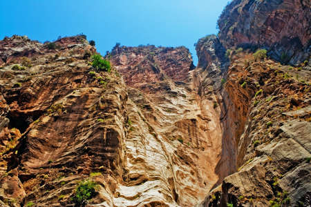 View from the bottom up on a steep wall of rockの写真素材