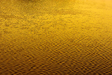 Water surface with ripples at sunset. Yellow texture.の写真素材