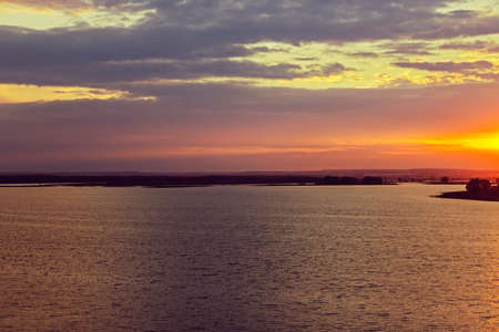 Landscape with a river and sunset over the cloudsの写真素材