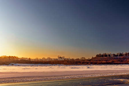 panorama of the frozen river and city on a cold winter evening