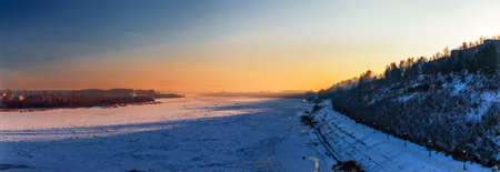 panorama of the frozen river and city on a cold winter eveningの写真素材