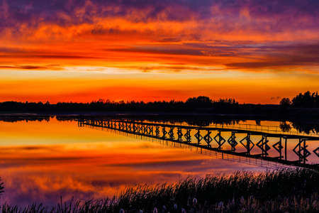 old iron footbridge on the lake at sunsetの写真素材
