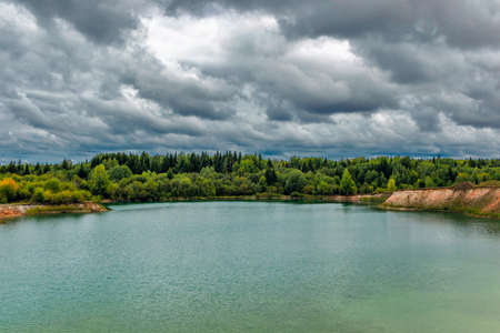 lake near the forest on a cloudy gloomy summer dayの写真素材