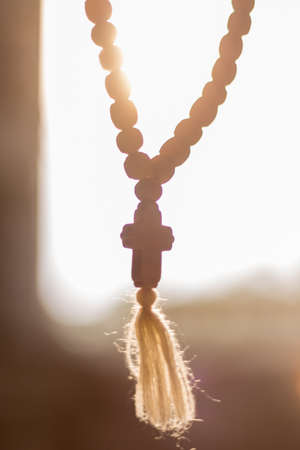 Christian wooden prayer rosary with cross against the sunの写真素材