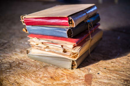 Pile of old documents in colorful cardboard folders in warm sunlight