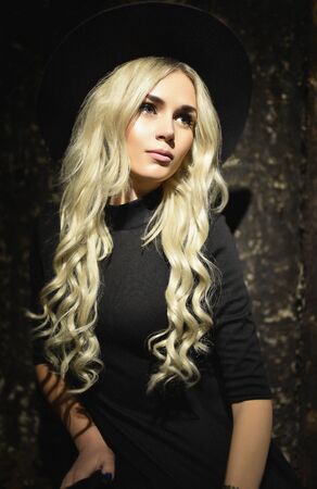 The beautiful girl with long curly hair in a black hatの写真素材