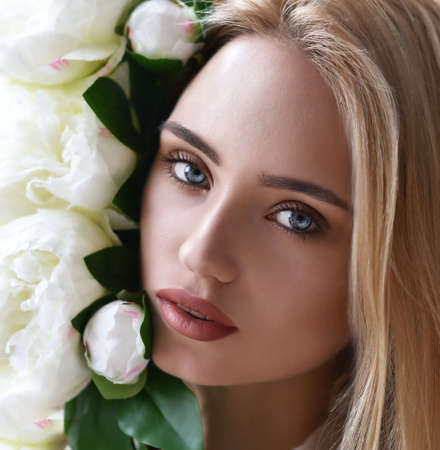 beauty portrait of young blonde girl with peony flower in her hands on grey backgroundのeditorial素材