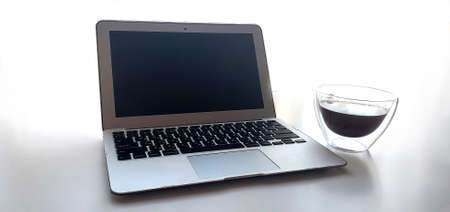 Still-life portrait of grey computer with black buttons, coffee mug on table.