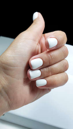 Tender hands with perfectwhite manicure on trendy pastel pink background. Place for text.の写真素材