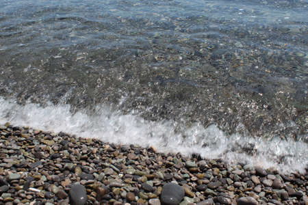 The sea waves beat against the shore. White foam waves of the sea. Pebble beach beach