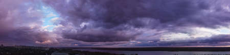 purple sunset with clouds over the city. sky panorama with colorful clouds for wallpaper design. dramatic cloud skyの写真素材